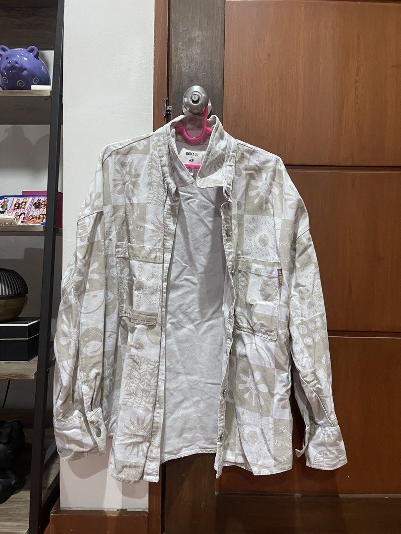 H&M Smiley oversized denim jacket (Category: Shirts) located in Cainta. Submitted by engelerrrr (Listing ID 1422966650, Image 1). Description: - H&M x Smiley collaboration shirt - Size: M - Color: Beige and white - Features: Button-down front, two chest pockets, long sleeves - Design: Unique pattern with smiley faces.