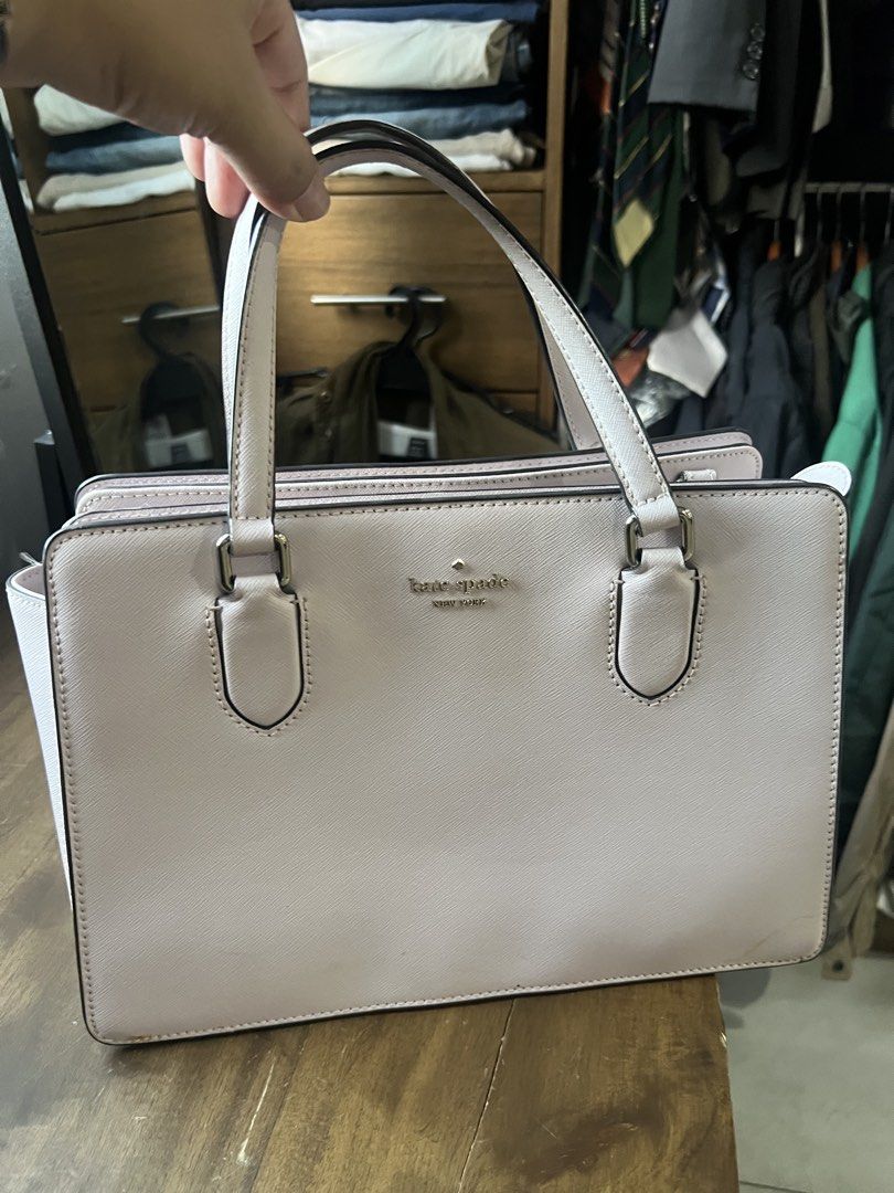 Kate Spade New York Handbag (Category: Luxury Bags & Wallets) located in Paranaque City. Submitted by amberprelovedstuff (Listing ID 1423005548, Image 3). Description: - Light pink almost white Kate Spade handbag - Features two handles - Rectangular shape - Kate Spade New York logo on the front - Structured design - Spacious interior - Includes a side pocket - Made of smooth material.