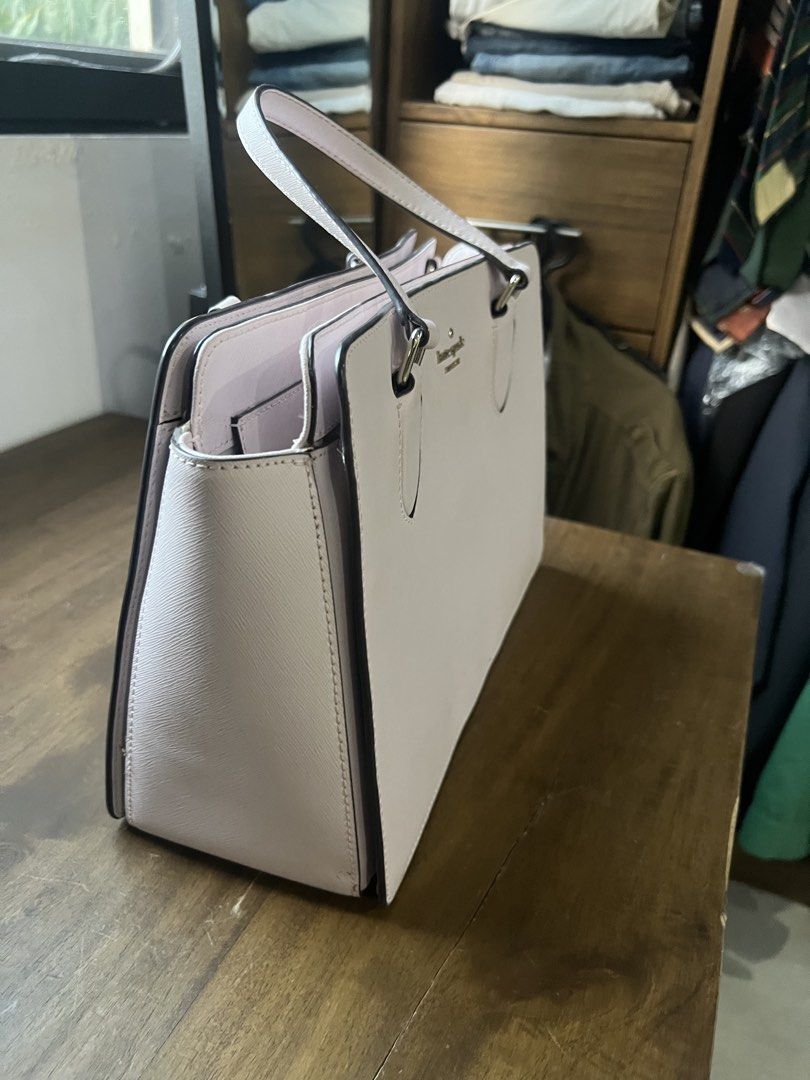 Kate Spade New York Handbag (Category: Luxury Bags & Wallets) located in Paranaque City. Submitted by amberprelovedstuff (Listing ID 1423005548, Image 2). Description: - Light pink almost white Kate Spade handbag - Features two handles - Rectangular shape - Kate Spade New York logo on the front - Structured design - Spacious interior - Includes a side pocket - Made of smooth material.