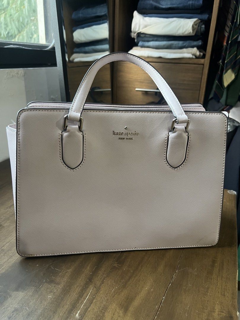 Kate Spade New York Handbag (Category: Luxury Bags & Wallets) located in Paranaque City. Submitted by amberprelovedstuff (Listing ID 1423005548, Image 1). Description: - Light pink almost white Kate Spade handbag - Features two handles - Rectangular shape - Kate Spade New York logo on the front - Structured design - Spacious interior - Includes a side pocket - Made of smooth material.