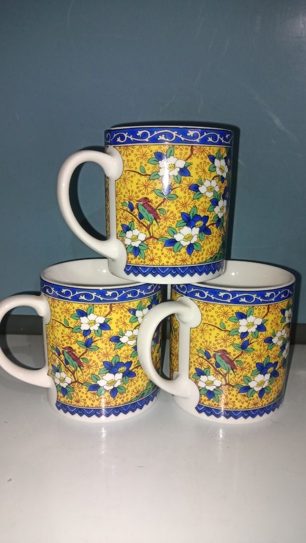 Kutani Maruishi Mug 150 each (Category: Coffee & Tea Tableware) located in Munoz. Submitted by larryc1212 (Listing ID 1423070362, Image 1). Description: Set of three vintage mugs featuring a vibrant yellow background with a floral and bird design. Each mug has a white handle and a blue rim. The mugs appear to be of a standard size, suitable for coffee or tea. The bottom of the mug has a green sticker. The mugs are approximately 3 inches in diamet