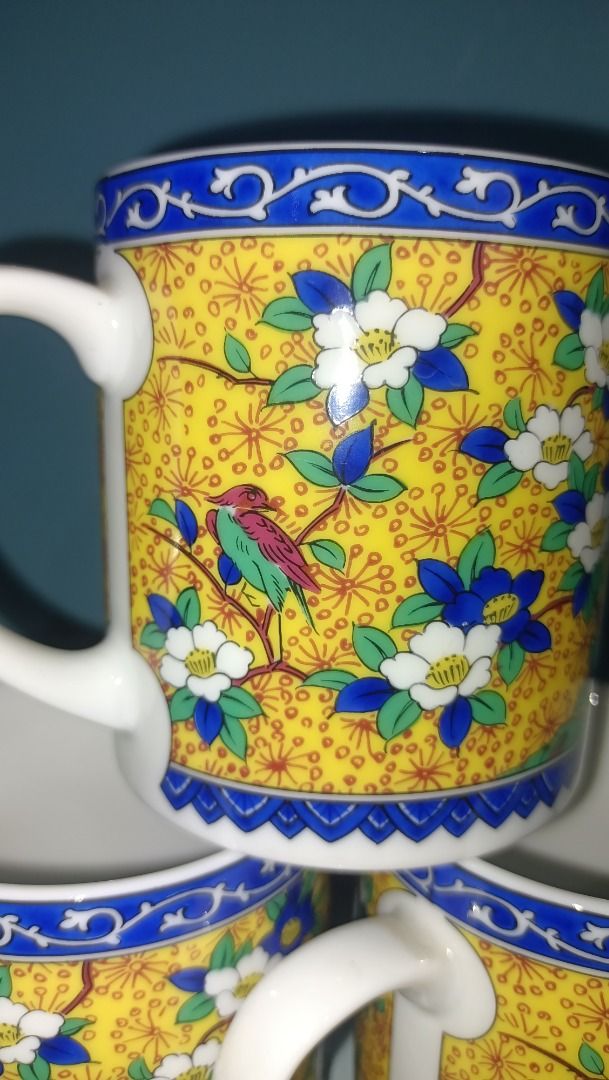 Kutani Maruishi Mug 150 each (Category: Coffee & Tea Tableware) located in Munoz. Submitted by larryc1212 (Listing ID 1423070362, Image 2). Description: Set of three vintage mugs featuring a vibrant yellow background with a floral and bird design. Each mug has a white handle and a blue rim. The mugs appear to be of a standard size, suitable for coffee or tea. The bottom of the mug has a green sticker. The mugs are approximately 3 inches in diamet