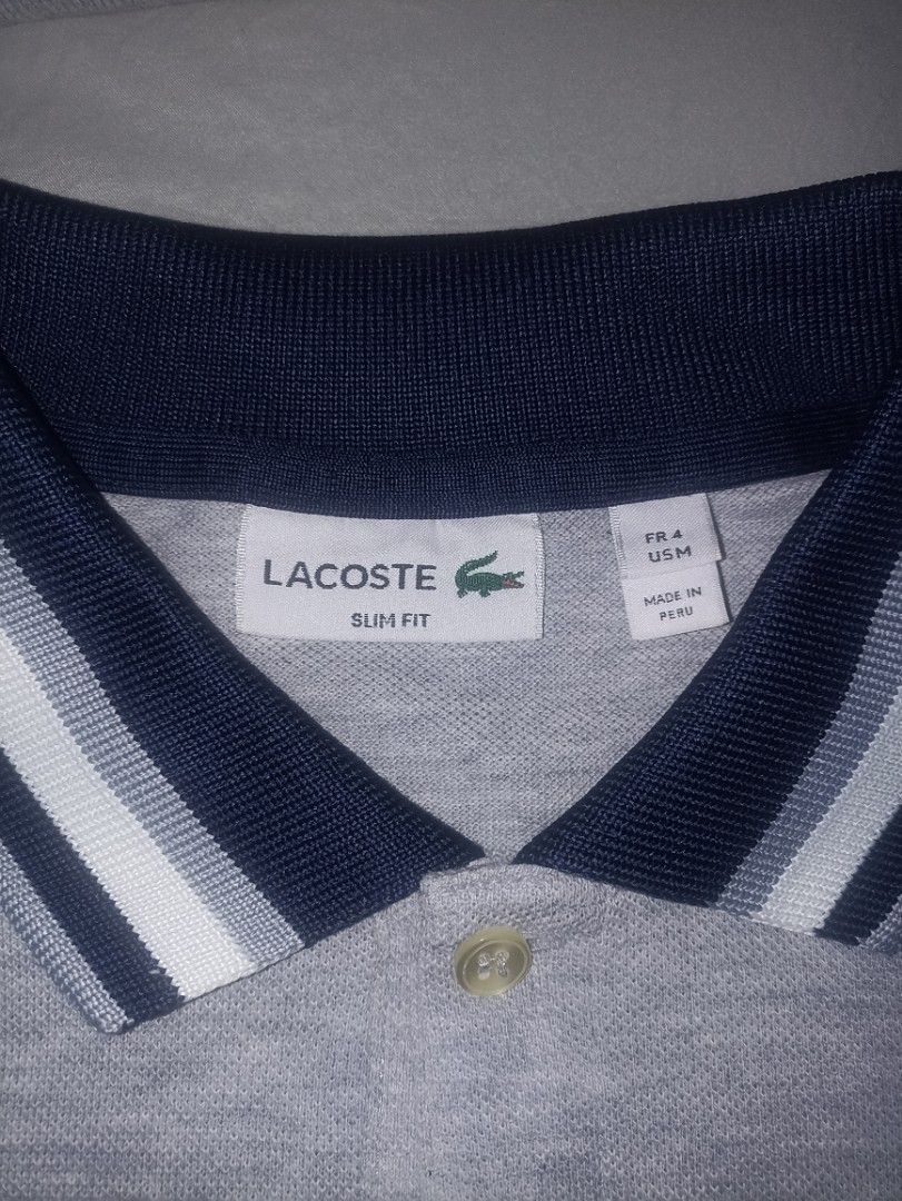 Lacoste Slim Fit Polo Shirt (Category: Tshirts & Polo Shirts ) located in Manila. Submitted by freespace01 (Listing ID 1422936098, Image 1). Description: - Lacoste slim-fit polo shirt - Color: Gray - Navy and white striped collar and sleeve cuffs - Lacoste logo on chest - Two-button placket - Made in Peru slightly used, looks good still.