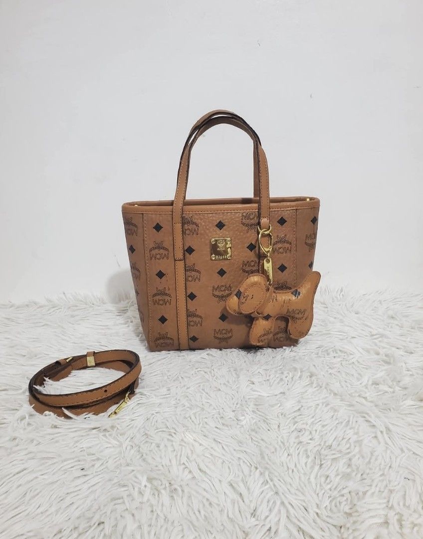 MCM Basket Bag Female Handbag Messenger (Category: Luxury Bags & Wallets) located in Malaybalay. Submitted by sparow088 (Listing ID 1422927604, Image 2). Description: - Authentic MCM basket bag - Includes a cute dog charm - Features a top handle and a detachable strap for versatility - Showcases the iconic MCM logo pattern - Interior boasts a patterned lining and a secure zippered pocket - Elegant brown color.