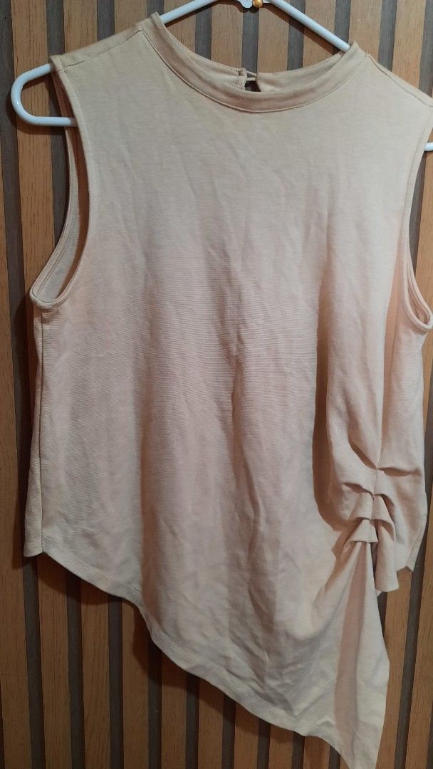 Skin tone Sleeveless Top (Category: Sleeveless) located in Caloocan City. Submitted by maxineshop (Listing ID 1423016017, Image 2). Description: - Asymmetrical sleeveless top - Soft skin tone color - Round neckline - Flowing, draped side detail - Lightweight fabric - Perfect for warm weather - Versatile for various outfits.
