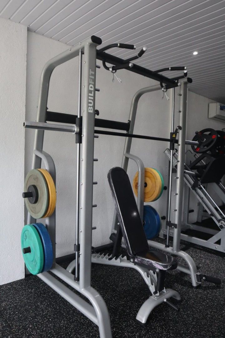 Smith Machine (Category: Cardio & Fitness Machines) located in Caloocan City. Submitted by protein888 (Listing ID 1422947697, Image 3). Description: Buildfit Smith Machine with adjustable bench. Features a pull-up bar and weight storage pegs. Includes a barbell. Suitable for various exercises. The machine is sturdy and designed for home or commercial gyms. The bench is adjustable for different angles. The frame is made of durable metal..