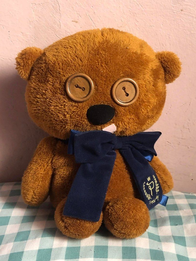 Tim Bear Brown Teddy Bear with Button Eyes (Category: Plushies & Soft Toys) located in Manila. Submitted by 102598iris (Listing ID 1422917352, Image 3). Description: - Adorable brown teddy bear - Features button eyes and a navy blue bow - Soft, plush material - Includes a black nose and a small white detail on the mouth - Comes with a tag featuring a logo on the bow - Ideal for cuddling or decoration.
