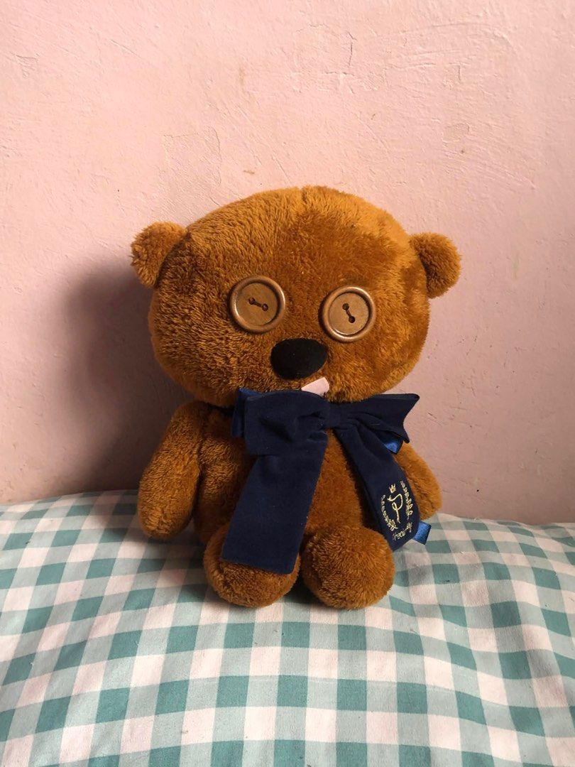 Tim Bear Brown Teddy Bear with Button Eyes (Category: Plushies & Soft Toys) located in Manila. Submitted by 102598iris (Listing ID 1422917352, Image 2). Description: - Adorable brown teddy bear - Features button eyes and a navy blue bow - Soft, plush material - Includes a black nose and a small white detail on the mouth - Comes with a tag featuring a logo on the bow - Ideal for cuddling or decoration.
