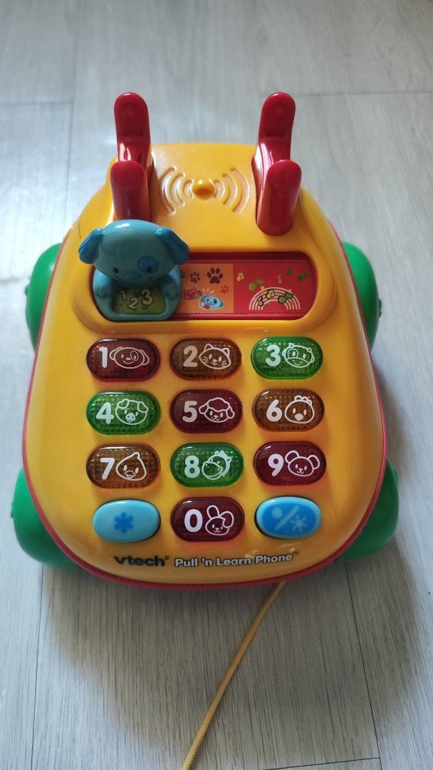 VTech Pull & Learn Phone (Category: Educational & Learning Toys) located in Cavite. Submitted by nesstuffandeverything (Listing ID 1422914603, Image 1). Description: - VTech Pull & Learn Phone for toddlers. - Features colorful buttons and animal sounds. - Includes a pull-along string. - Cute dog character and display with icons. - Helps children learn numbers. - Develops fine motor skills. - Yellow with green and red accents..