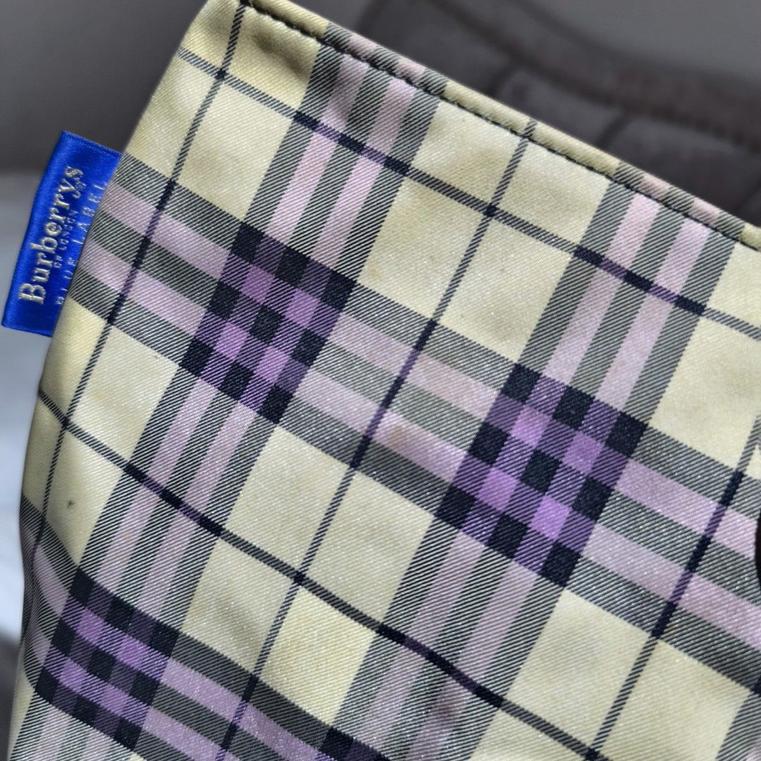 Burberrys Blue Label Tote Bag (Category: Luxury Bags & Wallets) located in Manila. Submitted by yui021 (Listing ID 1423221487, Image 2). Description: - Burberrys Blue Label tote bag with a classic plaid pattern in cream, purple, and black. - Features brown leather handles and a purple interior with a zippered pocket. - Includes a small tag with the Burberrys Blue Label logo. - Flaws shown in the pictures (stain on the canvas, damaged handle).