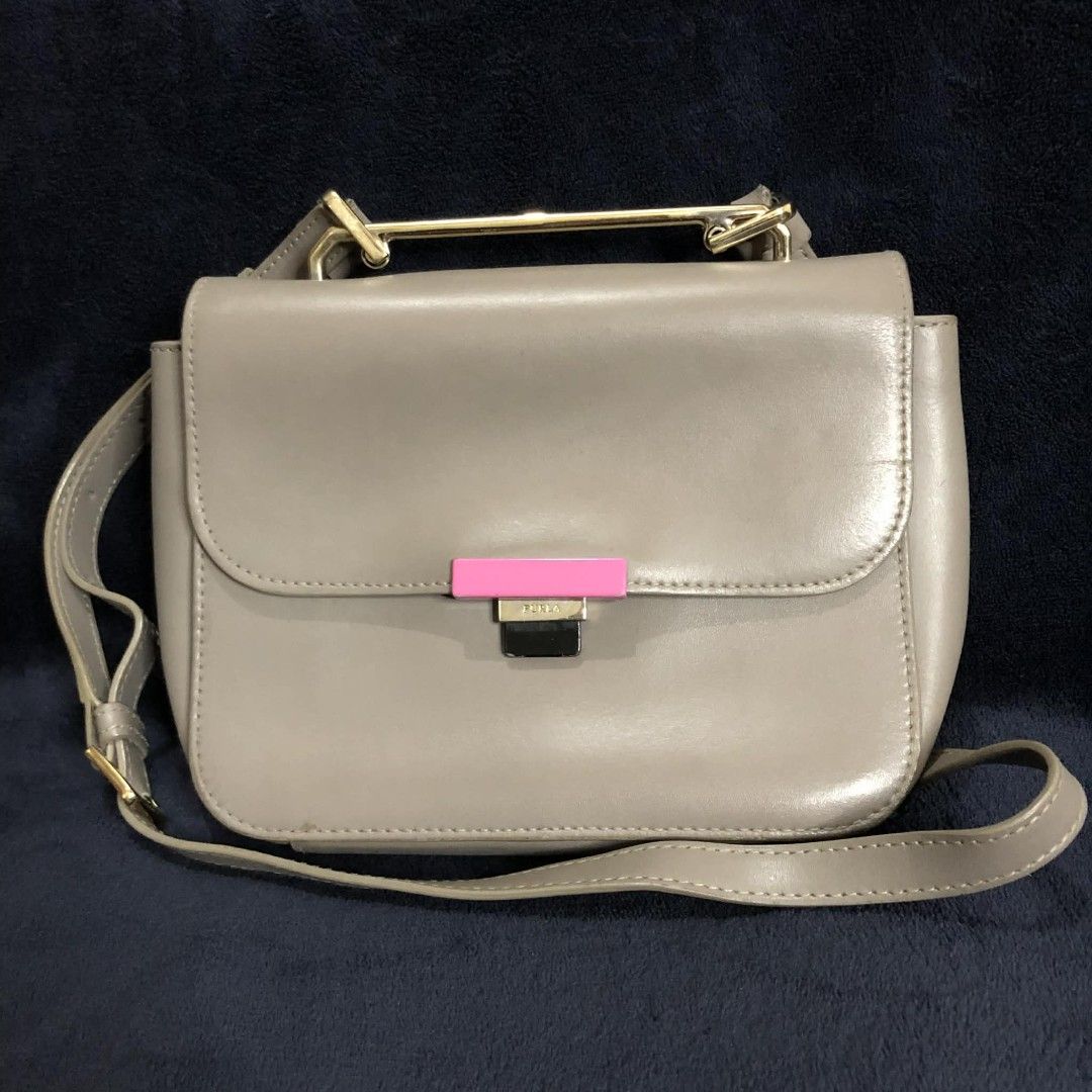 Furla Metropolis Crossbody Bag (Category: Luxury Bags & Wallets) located in Bayombong. Submitted by rnstrifty (Listing ID 1423254565, Image 1). Description: - Furla Metropolis crossbody bag - Grey leather exterior - Pink accent on clasp - Gold-tone handle - Detachable shoulder strap - Rectangular shape with flap closure - Furla logo visible.