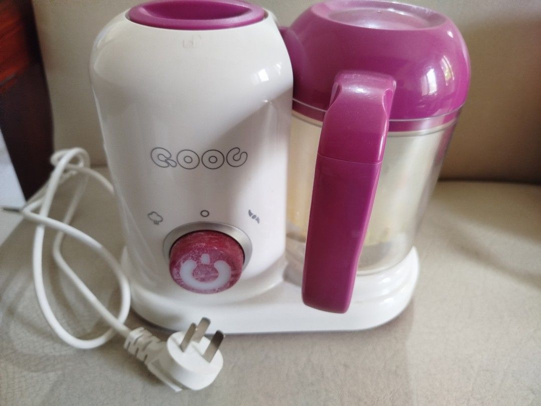 QOOG Baby Food Maker (Category: Weaning & Toddler Feeding) located in Quezon City. Submitted by carleldrin (Listing ID 1423140310, Image 1). Description: QOOG baby food maker with steaming and blending functions. Features a white and purple color scheme. Includes multiple components for food preparation. The base has a power cord with a three-pin plug. The unit has a dial for controlling the functions. The bottom of the unit has a sticker with sp