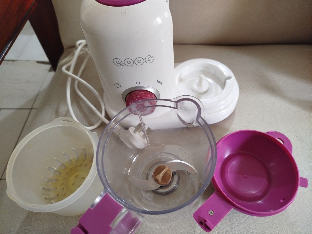 QOOG Baby Food Maker (Category: Weaning & Toddler Feeding) located in Quezon City. Submitted by carleldrin (Listing ID 1423140310, Image 2). Description: QOOG baby food maker with steaming and blending functions. Features a white and purple color scheme. Includes multiple components for food preparation. The base has a power cord with a three-pin plug. The unit has a dial for controlling the functions. The bottom of the unit has a sticker with sp