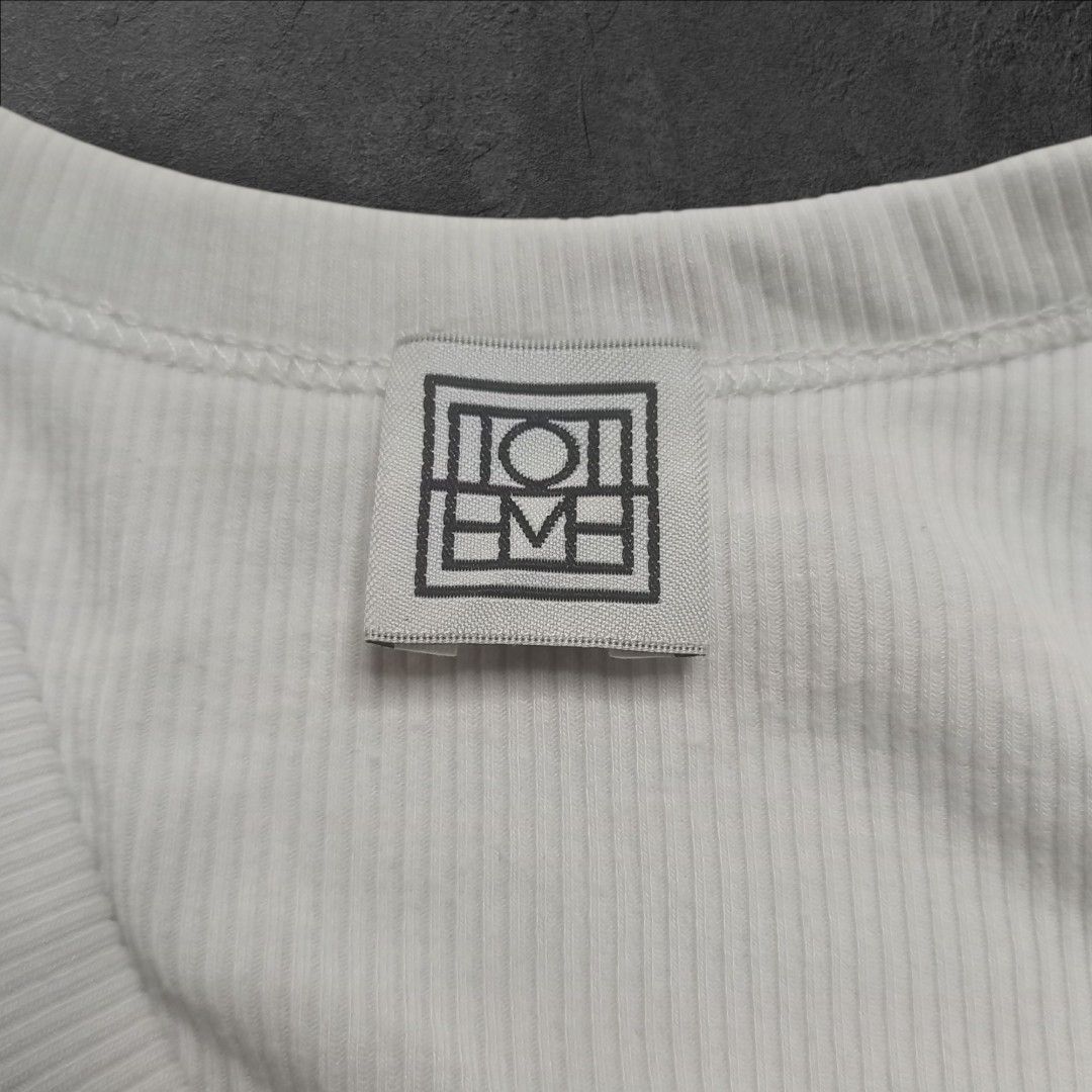 Toteme Studio Ribbed Tank Top (Category: Sleeveless) located in Alaminos. Submitted by thriftpill0302 (Listing ID 1423134413, Image 2). Description: - Toteme Studio white ribbed tank top - Excellent condition (Still presentable) - Width: 13½ can stretch up to 17 - Length: 22½ - Actual color: White - Color may appear lighter or darker due to lighting.