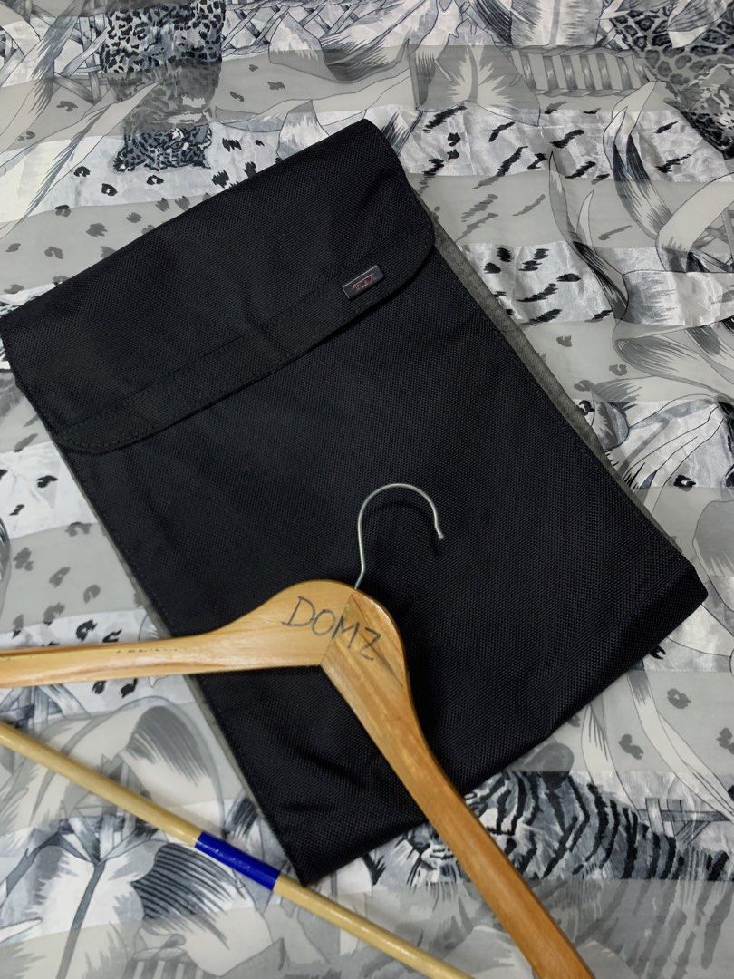 Tumi Laptop Sleeve (Category: Laptop Bags & Sleeves) located in Polomolok. Submitted by domingthriftclothes (Listing ID 1423124391, Image 3). Description: - Black Tumi laptop sleeve - Main compartment and front pocket - Interior with multiple compartments - Made of durable, textured material - Tumi logo visible - Includes a wooden hanger.