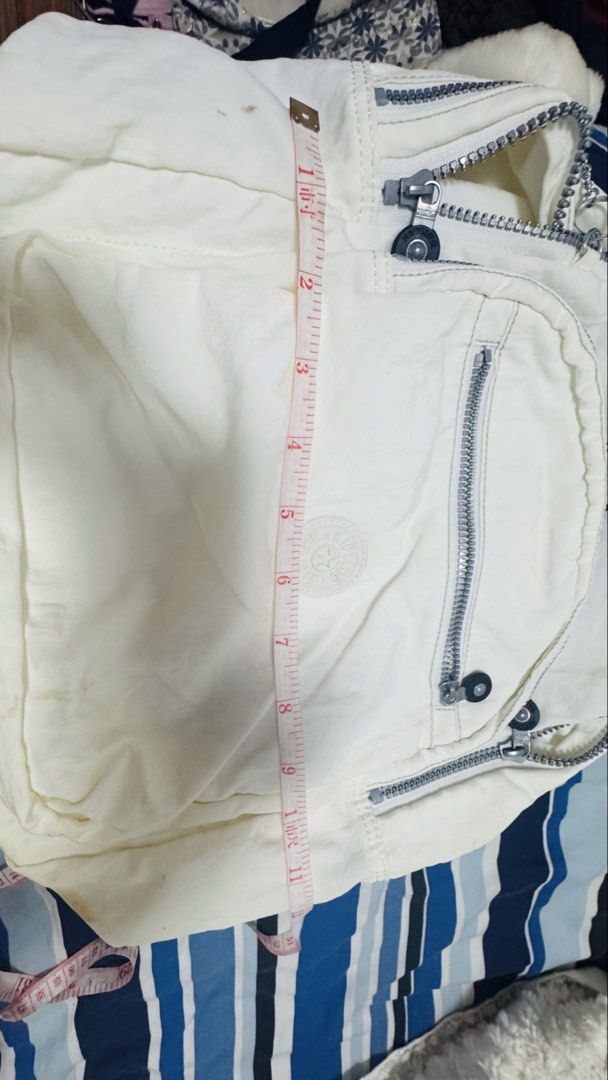 2026 Large beige Kipling Backpack (Category: Backpacks) located in Silang. Submitted by sari2bilina (Listing ID 1423304004, Image 2). Description: White Kipling backpack with multiple zippered compartments. Includes a small monkey keychain. The backpack has a top handle and adjustable straps. The interior is a light color. There are some stains on the exterior of the bag. The bag measures approximately 14 inches in height and 3 inches in width. w