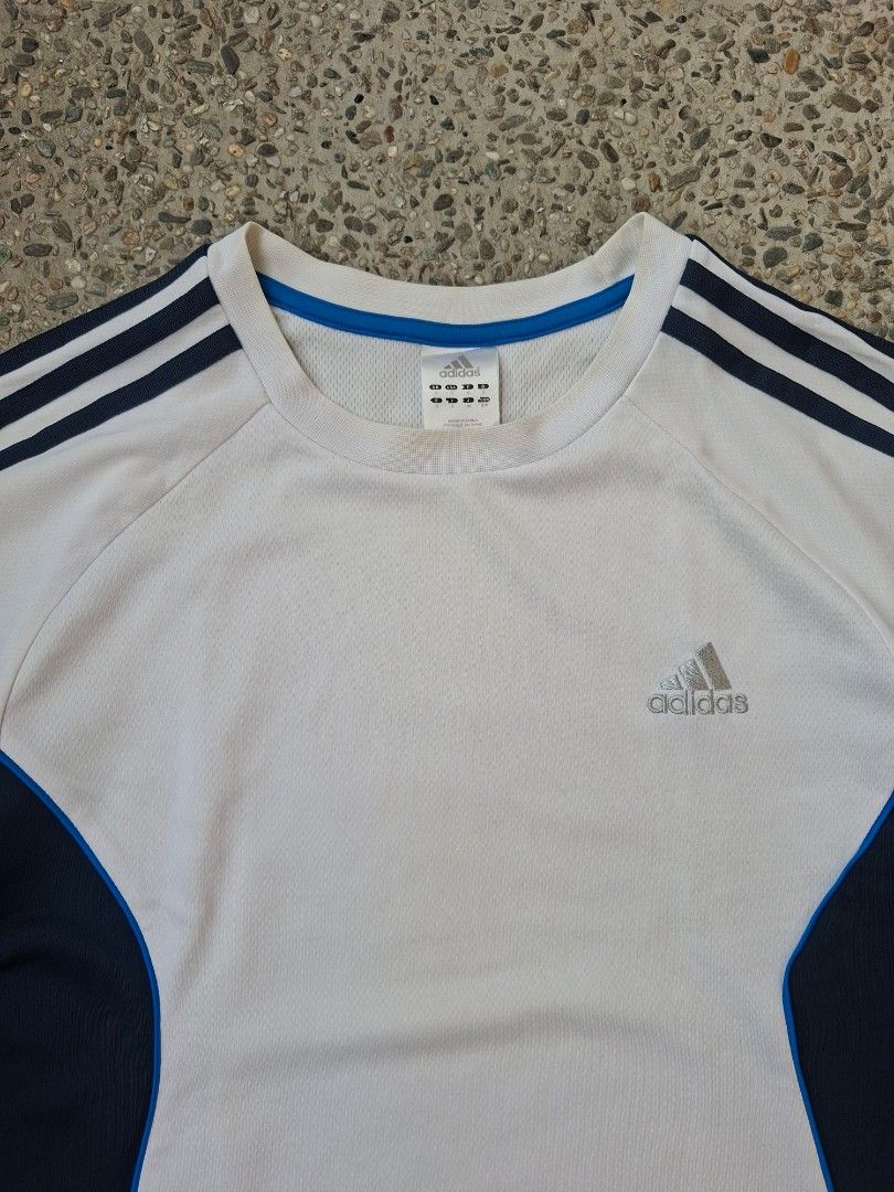 Adidas Climalite White T-shirt (Category: Tshirts & Polo Shirts ) located in Marikina City. Submitted by 2nd_chancedrips (Listing ID 1423382661, Image 2). Description: s on tag 19 x 26 -embroidered logo need wash Adidas Climalite white t-shirt with navy blue accents. Features the Adidas logo on the chest and three stripes on the sleeves. The tag indicates a size and manufacturing details. Made with Climalite fabric for moisture-wicking properties