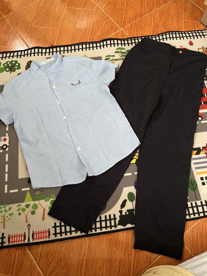 Boys' Shirt and Pants Set (Category: Babies & Kids Fashion) located in Las Pinas. Submitted by fechai (Listing ID 1423369293, Image 2). Description: Set includes a light blue short-sleeved shirt and black pants. The shirt has a mandarin collar and a small embroidered design. The pants are a solid black color. This outfit is suitable for casual or semi-formal occasions..