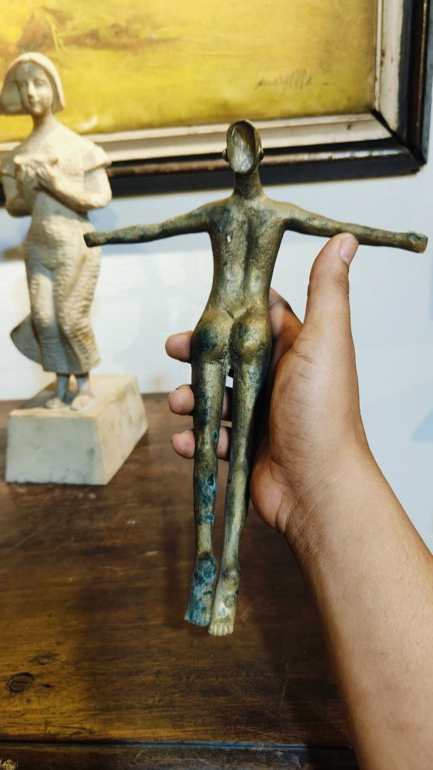 Brass U.P Oblation Sculpture (Category: Other Home Decor) located in Manila. Submitted by makkieenri69972 (Listing ID 1423301386, Image 3). Description: - Bronze sculpture of a female figure - Features outstretched arms - Dark, aged patina - Held in a hand, showcasing details - Stands on a wooden surface - Another sculpture visible in the background.