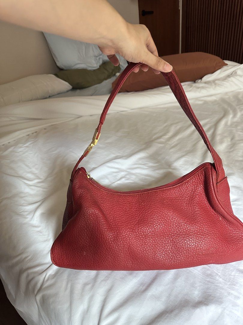 Christian Daniel Red Leather Shoulder Bag (Category: Shoulder Bags) located in Tabuk. Submitted by classicseconds (Listing ID 1423272152, Image 1). Description: - Christian Daniel shoulder bag - Red leather - Zip closure - Single shoulder strap - Gold-tone buckle - Textured leather exterior - Interior zippered pocket - Brown lining - Small back pocket.