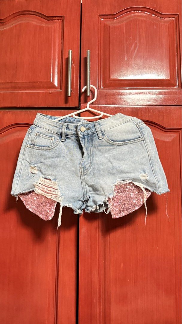 Distressed Denim Shorts with Sequin Detail (Category: Shorts) located in Amadeo. Submitted by beaflr (Listing ID 1423406801, Image 1). Description: - Light wash denim shorts - Distressed detailing - Button and zipper closure - Pink sequin accents on front - Size 26-27.