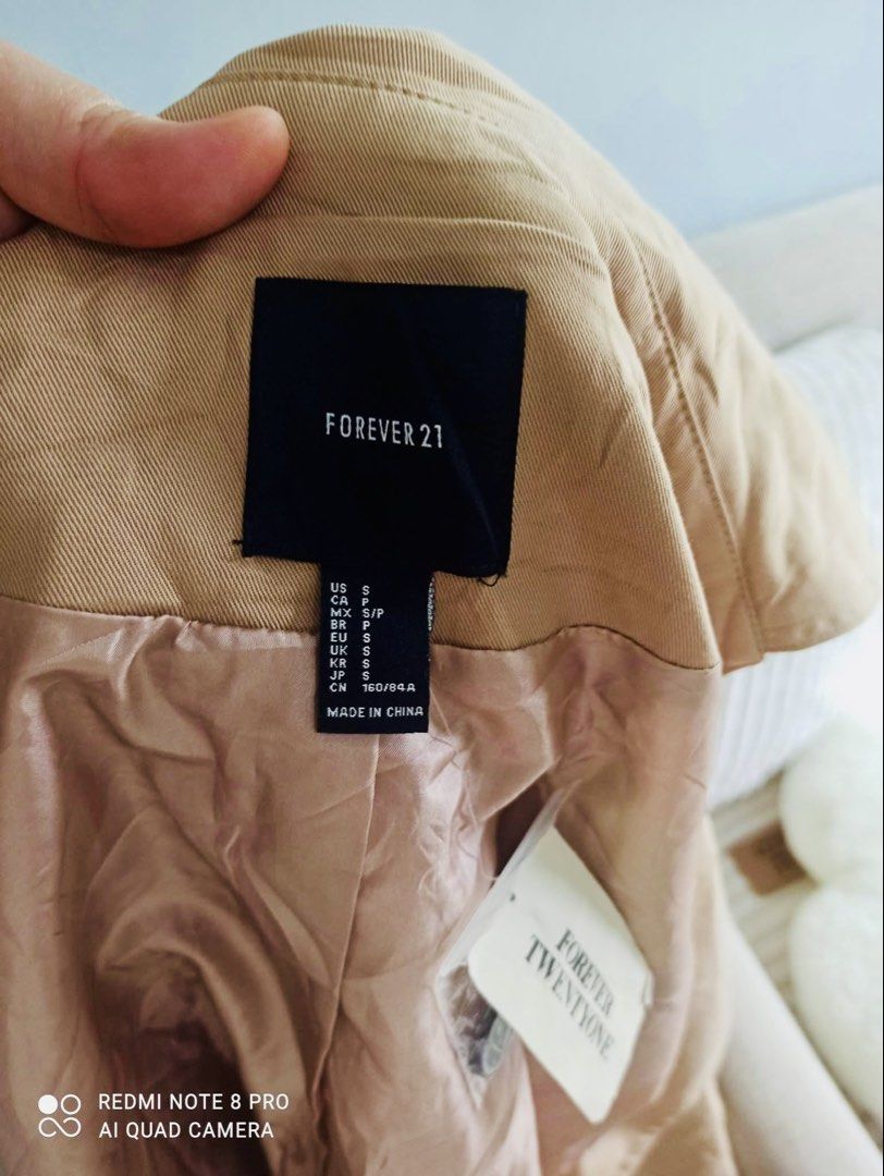 Forever 21 Trench Coat - Size S (Category: Coats, Jackets and Outerwear) located in San Juan City. Submitted by niqclassythrift (Listing ID 1423381138, Image 2). Description: - Forever 21 tan trench coat - Size: S - Double-breasted design - Features buttons - Classic trench coat style - Collar and long sleeves - Made in China.
