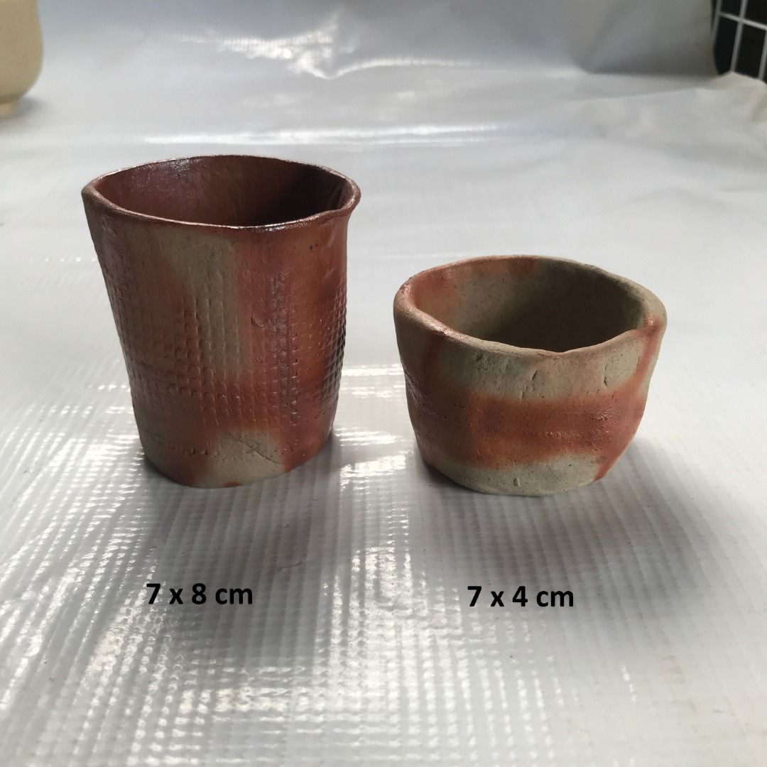 Handmade Pottery Cups Set #4360 (Category: Coffee & Tea Tableware) located in Malabon City. Submitted by mldg.surplus (Listing ID 1423366257, Image 1). Description: Set of two handmade pottery cups. One cup measures 7x8 cm, and the other measures 7x4 cm. Both cups feature a unique reddish-brown and beige color scheme. The larger cup has a textured exterior, while the smaller cup has a smooth finish. Perfect for adding a touch of artistry to your 