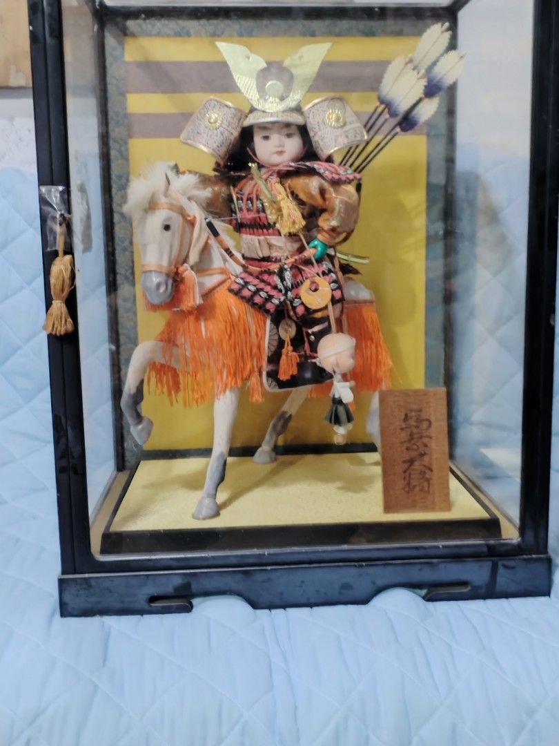 Japanese Samurai Figurine in Glass Case (Category: Vintage Collectibles) located in Caloocan City. Submitted by rowely_jpn (Listing ID 1423304525, Image 2). Description: Detailed Japanese samurai figurine riding a horse, encased in a glass display. The figurine is adorned with traditional armor, a helmet, and arrows. The display case has a black frame and a wooden base. The dimensions of the case are approximately 22 x 15 3/4 inches..