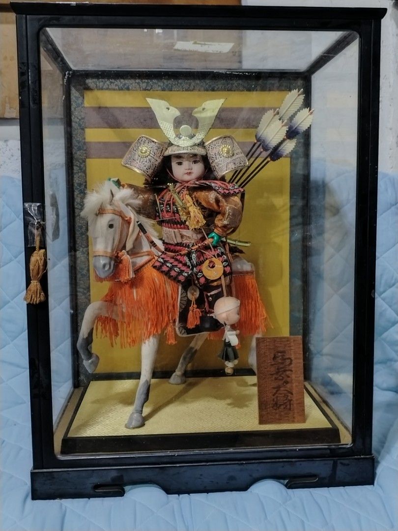 Japanese Samurai Figurine in Glass Case (Category: Vintage Collectibles) located in Caloocan City. Submitted by rowely_jpn (Listing ID 1423304525, Image 3). Description: Detailed Japanese samurai figurine riding a horse, encased in a glass display. The figurine is adorned with traditional armor, a helmet, and arrows. The display case has a black frame and a wooden base. The dimensions of the case are approximately 22 x 15 3/4 inches..
