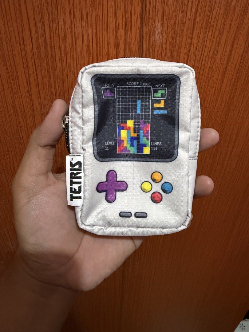 LeSportsac x Tetris Keyring Pouch (Category: Purses & Pouches) located in Dasmarinas. Submitted by markusi22 (Listing ID 1423302891, Image 1). Description: - LeSportsac x Tetris Keyring Pouch - Fun Tetris game design - Zipper closure - Keyring attachment - Interior lining with Tetris pattern - White pouch with black zipper - Tetris logo tag - Can be attached to a bag or used as a small pouch.