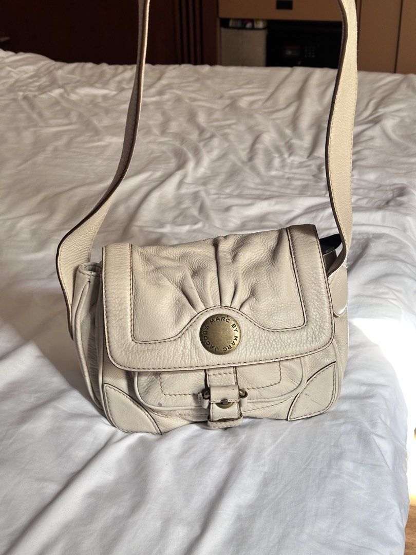 Marc by Marc Jacobs Cream Shoulder Bag (Category: Luxury Bags & Wallets) located in Tabuk. Submitted by classicseconds (Listing ID 1423267550, Image 1). Description: - Cream-colored Marc by Marc Jacobs shoulder bag - Flap closure with buckle - Gold-tone logo - Multiple interior compartments - Adjustable shoulder strap - Minor exterior marks.