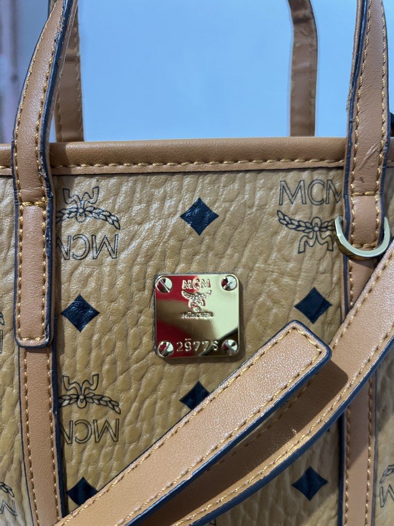 MCM Mini Tote Bag (Category: Luxury Bags & Wallets) located in Manila. Submitted by zoeykim16 (Listing ID 1423327990, Image 3). Description: - Authentic MCM mini tote bag - Brown exterior with MCM logo pattern - Detachable shoulder strap and top handles - Patterned interior lining - Zipper closure - Gold-tone metal logo plate - Minor wear on zipper.