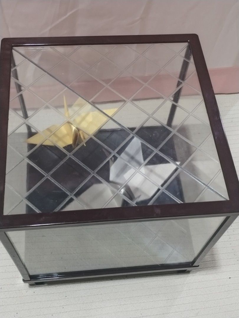 Origami Crane Display Case (Category: Storage Boxes & Baskets) located in Caloocan City. Submitted by rowely_jpn (Listing ID 1423302124, Image 1). Description: Elegant display case featuring two origami cranes. One crane is gold, and the other is silver. The case has a dark brown frame and a patterned base. The dimensions are approximately 9x9x9 inches. It has a clear glass top and sides, allowing for a full view of the origami art..