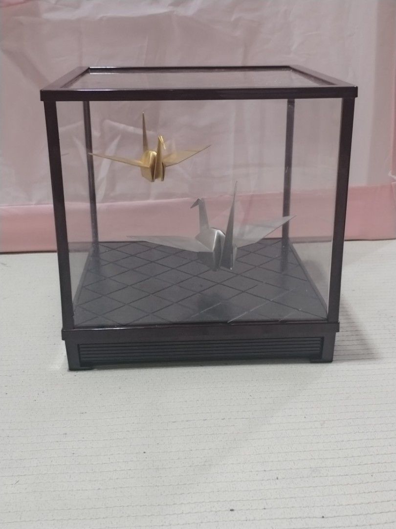 Origami Crane Display Case (Category: Storage Boxes & Baskets) located in Caloocan City. Submitted by rowely_jpn (Listing ID 1423302124, Image 2). Description: Elegant display case featuring two origami cranes. One crane is gold, and the other is silver. The case has a dark brown frame and a patterned base. The dimensions are approximately 9x9x9 inches. It has a clear glass top and sides, allowing for a full view of the origami art..