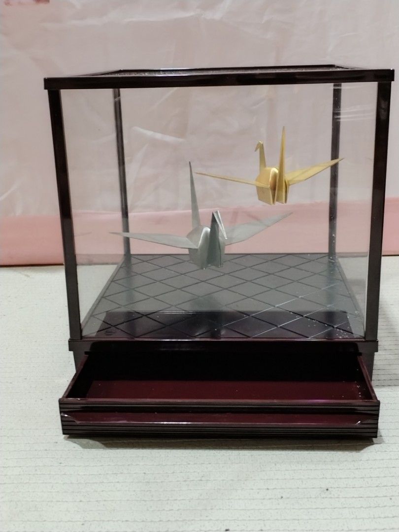 Origami Crane Display Case (Category: Storage Boxes & Baskets) located in Caloocan City. Submitted by rowely_jpn (Listing ID 1423302124, Image 3). Description: Elegant display case featuring two origami cranes. One crane is gold, and the other is silver. The case has a dark brown frame and a patterned base. The dimensions are approximately 9x9x9 inches. It has a clear glass top and sides, allowing for a full view of the origami art..