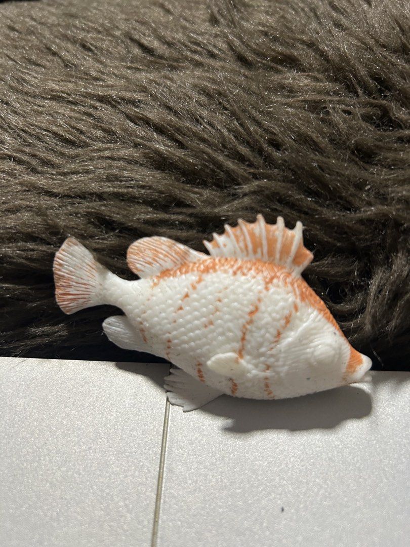 Plastic Fish Toy (Category: Kids Toys) located in Angeles City. Submitted by zyeplus (Listing ID 1423310756, Image 2). Description: - Adorable plastic fish toy. - Features a white body with orange accents. - Textured surface for added detail. - Small size, ideal for play or display. - Resting position..