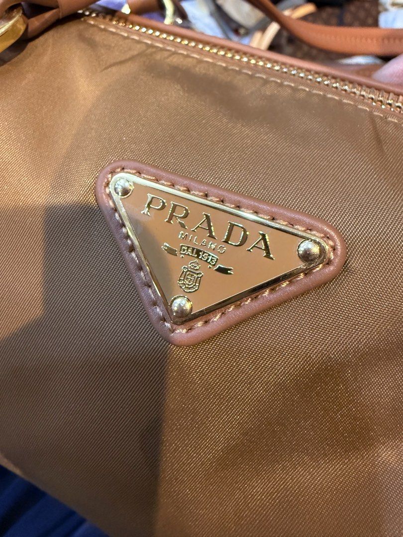 Prada Brown Nylon Handbag (Category: Luxury Bags & Wallets) located in Manila. Submitted by thebodega88 (Listing ID 1423314601, Image 2). Description: - Prada handbag - Brown nylon exterior - Gold-tone hardware - 'riri' zipper - Interior Prada logo - 'ECONYLO 100% REGENERATED NYLON' tag - Includes tag with number '165' NO ISSUE .