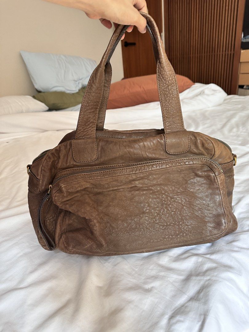 Rabeanco Genuine Leather Handbag (Category: Shoulder Bags) located in Tabuk. Submitted by classicseconds (Listing ID 1423270267, Image 1). Description: - rabeanco genuine leather handbag - Brown exterior - Zip closure - Two handles - Purple fabric lining - Interior zip pocket - Front pocket - Gold-tone hardware - "Genuine Leather" tag.