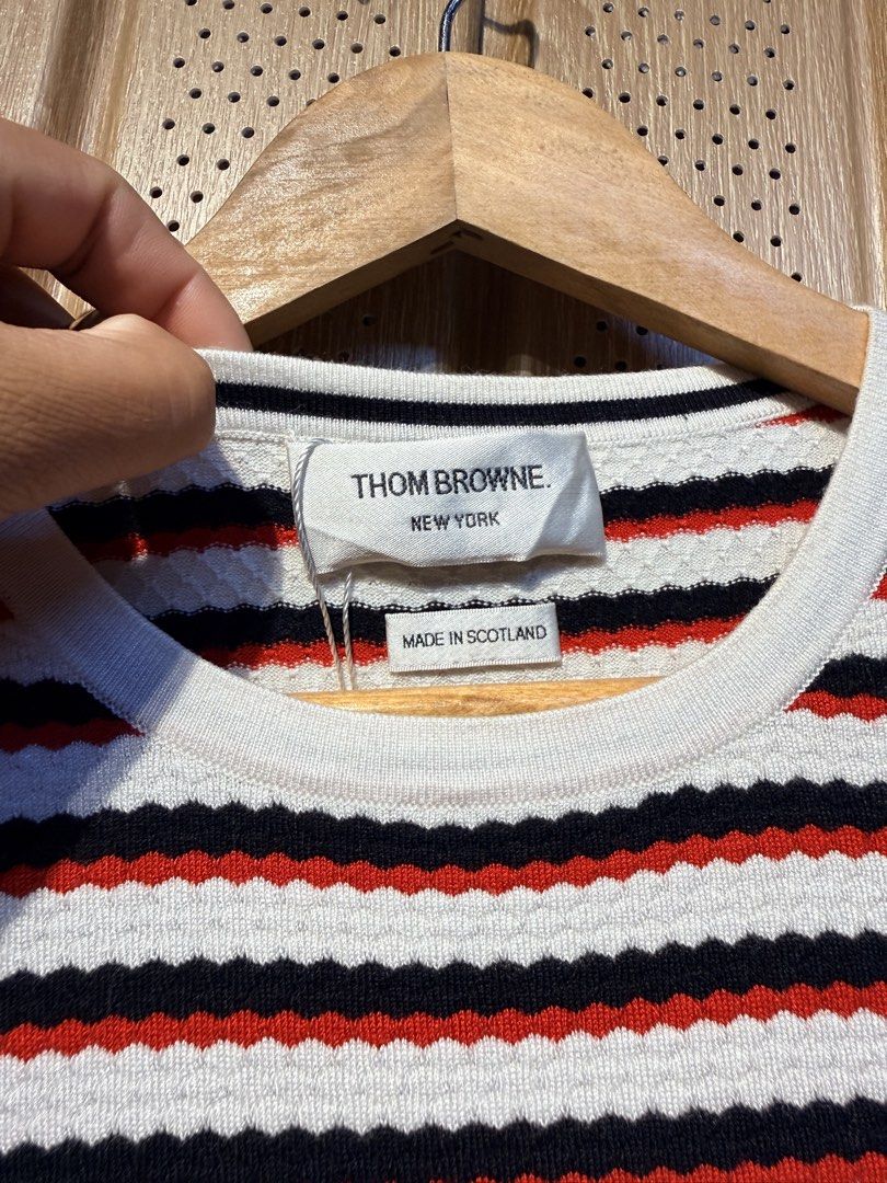Thom Browne Striped Knit Top (Category: Luxury Apparel) located in Santiago. Submitted by twicebutnice03 (Listing ID 1423336439, Image 2). Description: - Authentic Thom Browne knit top - Classic striped design (white, red, black) - Made in Scotland - Crew neck, short sleeves - Size S - Signature Thom Browne stripe detail at back of neck - 100% cotton.