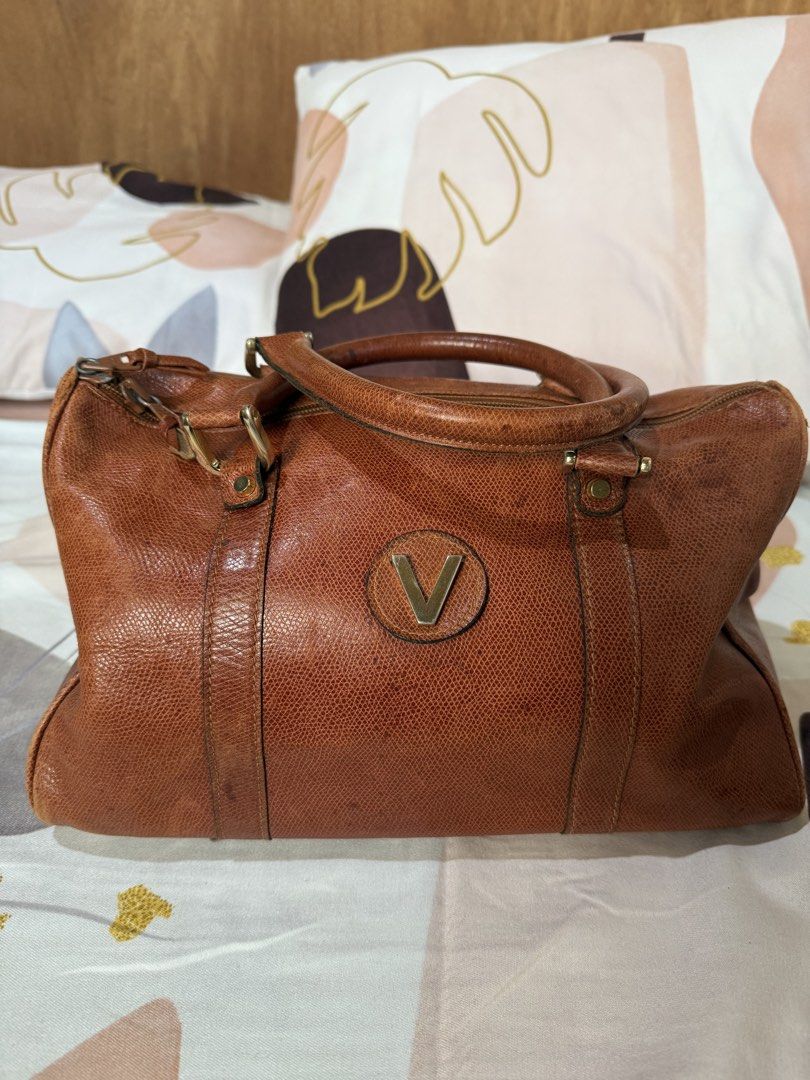 Vintage Brown Handbag with 'V' Logo (Category: Luxury Bags & Wallets) located in Manila. Submitted by izzycollections (Listing ID 1423267959, Image 1). Description: - Vintage brown handbag - 'V' logo on front - Top handle - Zipper closure - Textured leather exterior - Gold-toned hardware - Signs of wear on handles and corners.