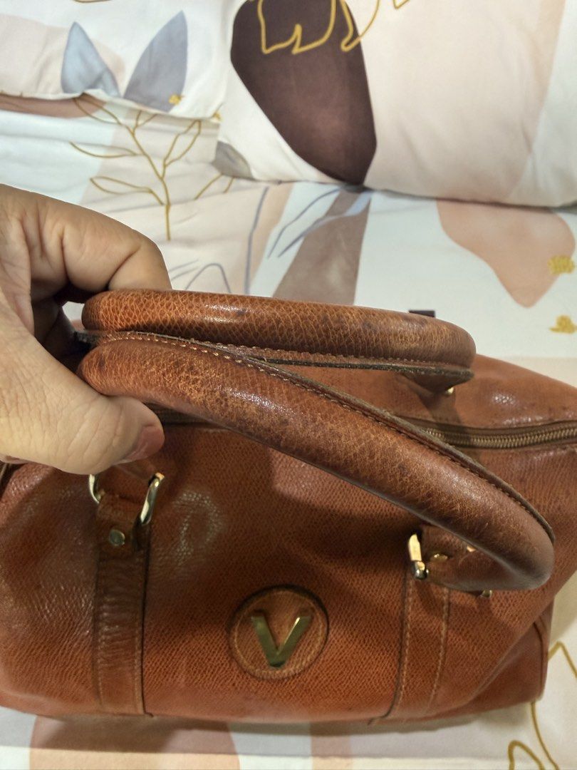 Vintage Brown Handbag with 'V' Logo (Category: Luxury Bags & Wallets) located in Manila. Submitted by izzycollections (Listing ID 1423267959, Image 3). Description: - Vintage brown handbag - 'V' logo on front - Top handle - Zipper closure - Textured leather exterior - Gold-toned hardware - Signs of wear on handles and corners.