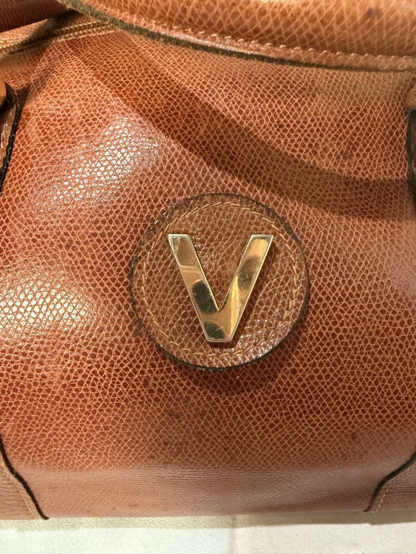 Vintage Brown Handbag with 'V' Logo (Category: Luxury Bags & Wallets) located in Manila. Submitted by izzycollections (Listing ID 1423267959, Image 2). Description: - Vintage brown handbag - 'V' logo on front - Top handle - Zipper closure - Textured leather exterior - Gold-toned hardware - Signs of wear on handles and corners.