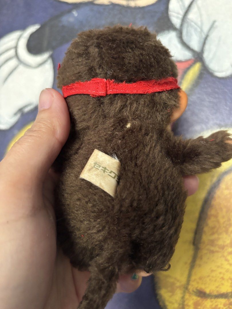 Vintage Monchhichi Plush Toy (Category: Plushies & Soft Toys) located in Quezon City. Submitted by coramalabanan (Listing ID 1423268831, Image 2). Description: - Adorable vintage Monchhichi plush toy - Features a brown fur body - Comes with a red headband - Smiling face - Plastic feet and face - Long brown tail - Includes original tag - A classic collectible item.