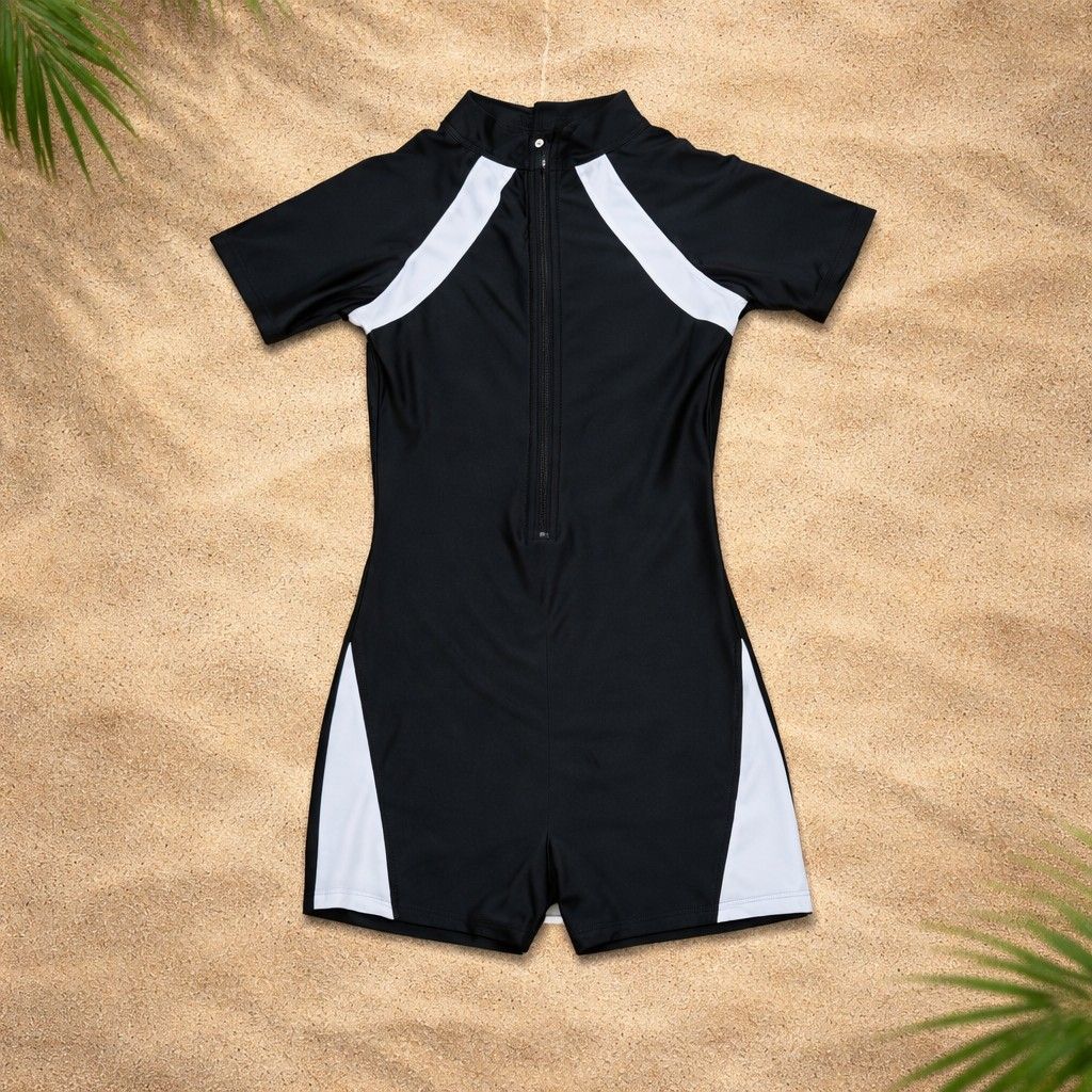 Black and White Swimsuit Rashguard (Category: Bikinis & Swimsuits) located in Quezon City. Submitted by gicasworld (Listing ID 1423562287, Image 1). Description: Swimsuit features a black base with white accents on the sides and shoulders. It has short sleeves and a zipper down the front. The swimsuit is a one-piece design with a high neckline and short legs. It is suitable for swimming or other water activities..