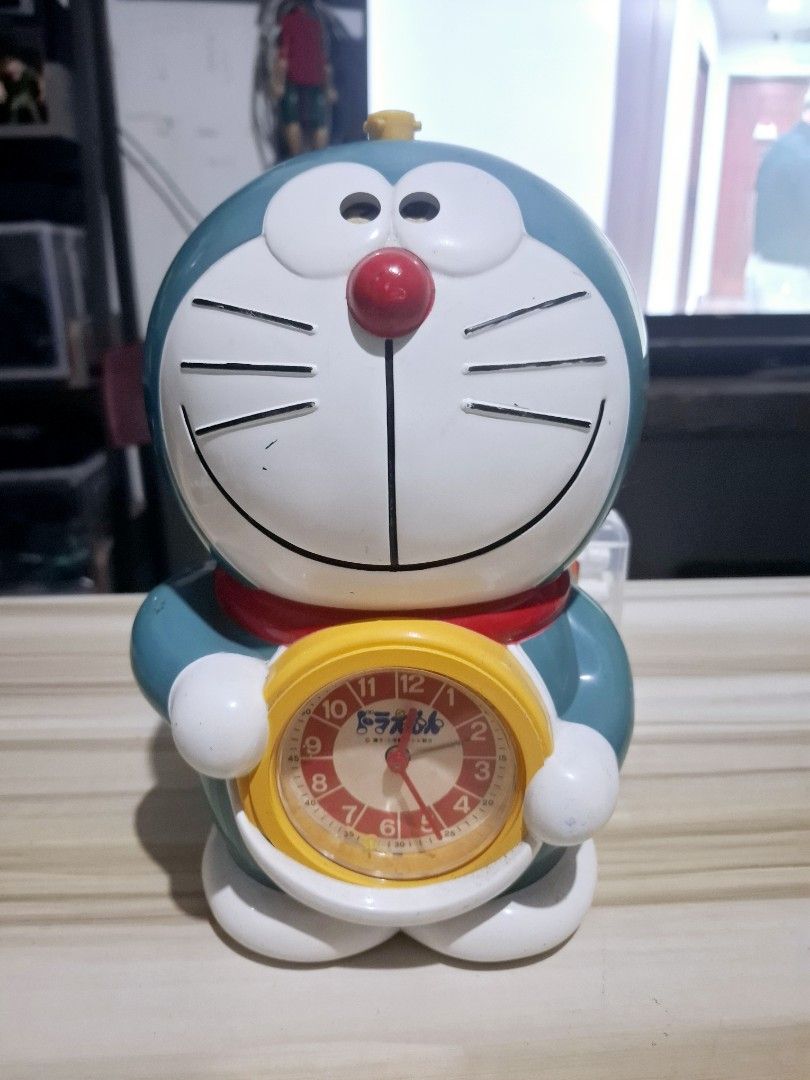 Doraemon Alarm Clock (Category: Clocks) located in Antipolo. Submitted by lakay_toys (Listing ID 1423578570, Image 1). Description: - Doraemon alarm clock - Classic design - Yellow clock face - Red nose and collar - Speaker and battery compartment at the back - Sticker at the bottom.