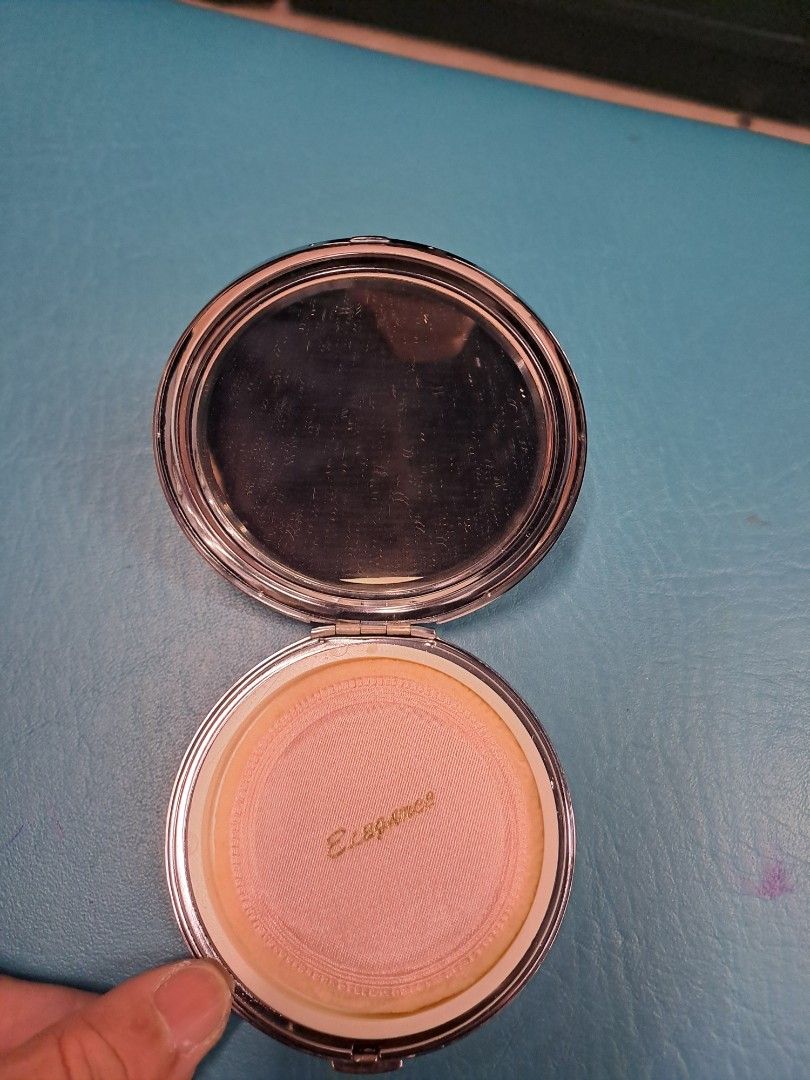 Elegance Powder Compact with Floral Design (Category: Makeup) located in Manila. Submitted by joanbalde39643 (Listing ID 1423531842, Image 2). Description: Elegant powder compact with a beautiful floral design on the lid. The compact includes a mirror and a powder compartment with a powder puff. The brand name "Elegance" is visible on the powder. The compact has a silver-colored frame. It is a round shape..