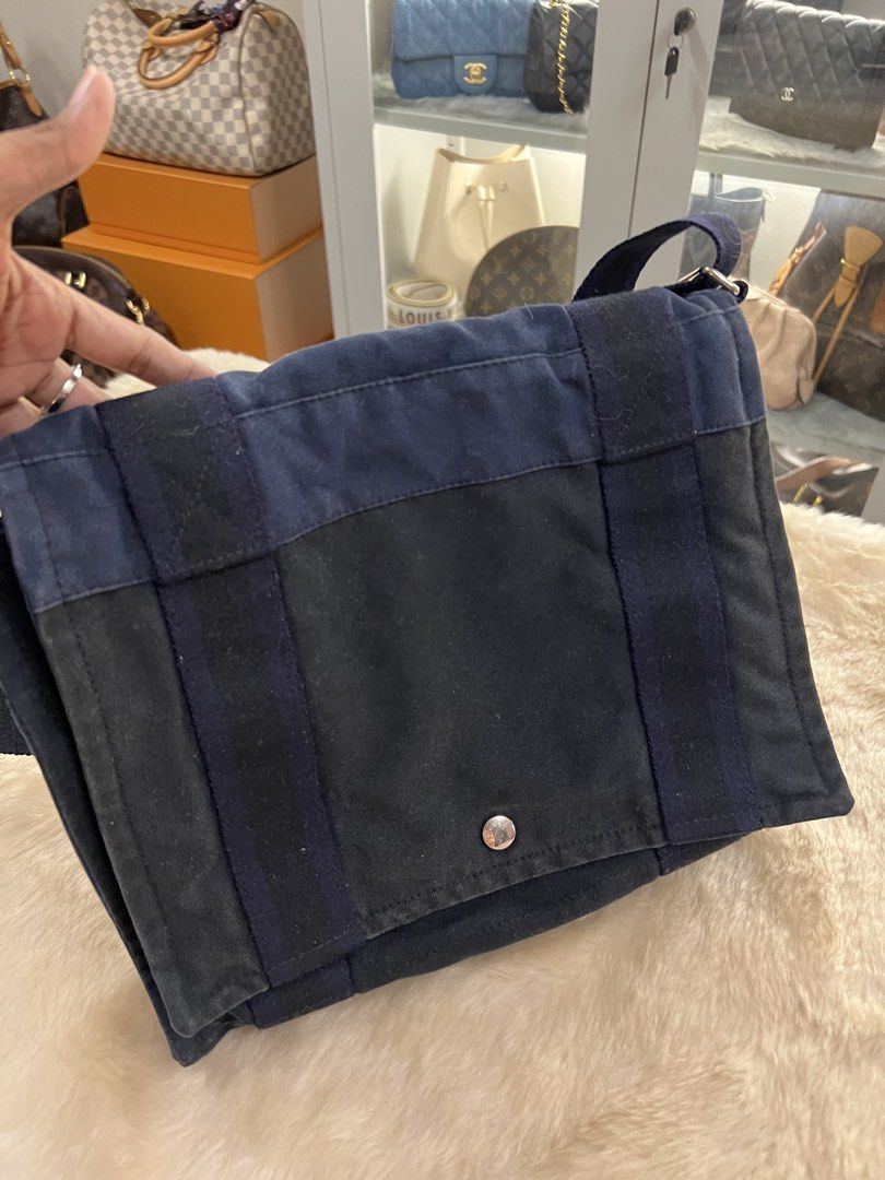 Hermes Canvas Messenger Bag (Category: Luxury Bags & Wallets) located in Manila. Submitted by murafinds26 (Listing ID 1423501641, Image 1). Description: - Hermes messenger bag - Navy and black canvas design - Flap closure with snap button - Adjustable shoulder strap - Interior zipper pocket - Approximately 12" length x 10" height.