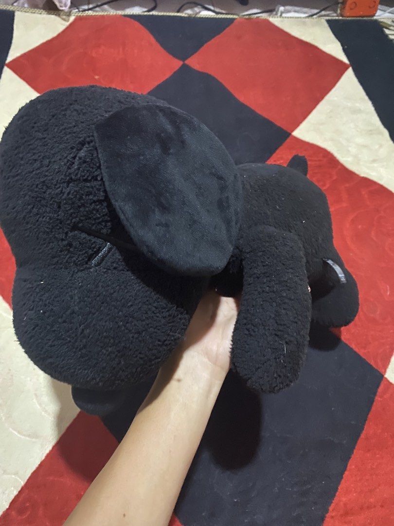 KAWS x Peanuts Snoopy Plush Toy (Category: Plushies & Soft Toys) located in Opol. Submitted by yashaofficial (Listing ID 1423476578, Image 2). Description: - KAWS x Peanuts Snoopy plush toy - Color: Black - Design: KAWS "XX" on one eye - Collaboration: Uniqlo - Pose: Snoopy lying down - Material: 100% Polyester.