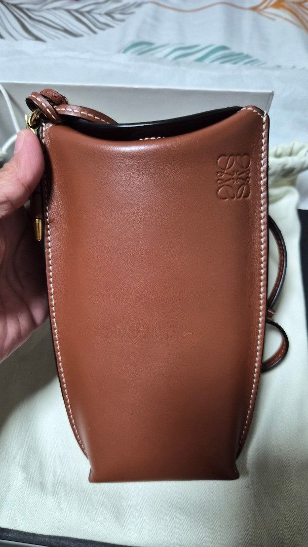 Loewe Leather Phone Bag (Gate Pocket) (Category: Luxury Bags & Wallets) located in Quezon City. Submitted by marya_s (Listing ID 1423459303, Image 2). Description: inclusions: box dustbag paper from Loewe and Receipt (japan bought) Loewe leather phone bag in a beautiful brown color. Features a detachable strap, interior card slot, and a soft interior lining. Comes with original box, dust bag, and tags. The bag has white stitching details and gold