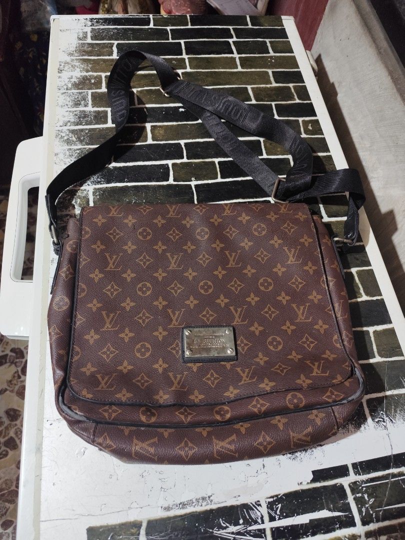 Louis Vuitton Messenger Bag (Category: Luxury Bags & Wallets) located in Lemery. Submitted by dailythriftin (Listing ID 1423516467, Image 1). Description: Louis Vuitton messenger bag. Features the iconic LV monogram pattern. Includes a shoulder strap with the Louis Vuitton logo. The bag has a front flap closure and a zippered pocket. The interior is lined with black fabric and includes a brand tag. The bag has a metal plate with the Louis Vuitton